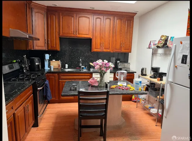 a kitchen with stainless steel appliances granite countertop a stove top oven a sink dishwasher and cabinets with wooden floor