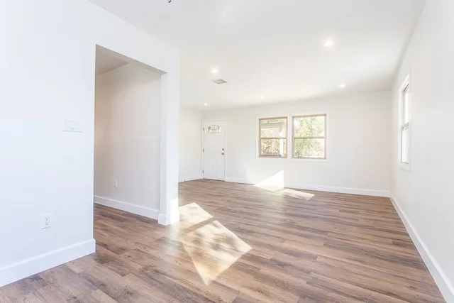 an empty room with wooden floor and windows
