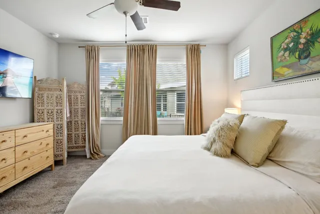 a spacious bedroom with a bed a dresser and a large window