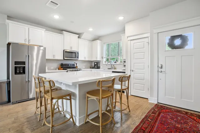 a kitchen with stainless steel appliances granite countertop a stove a refrigerator a microwave oven with a dining table and chairs