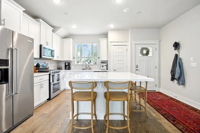 a kitchen with stainless steel appliances a dining table chairs refrigerator and sink