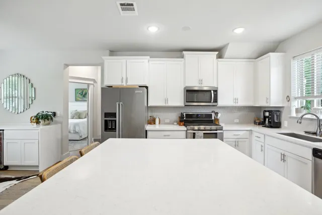 a kitchen with a refrigerator a stove top oven a sink a window and cabinets