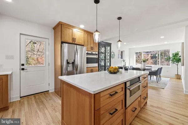 a kitchen with stainless steel appliances granite countertop a sink a stove a refrigerator and island with wooden floor