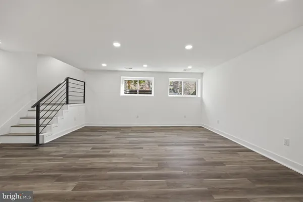 a view of an empty room with wooden floor and stairs