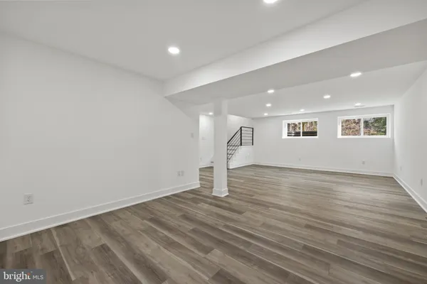 a view of an empty room with wooden floor fireplace and a window