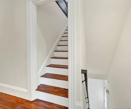 a view of staircase with wooden floor and white walls