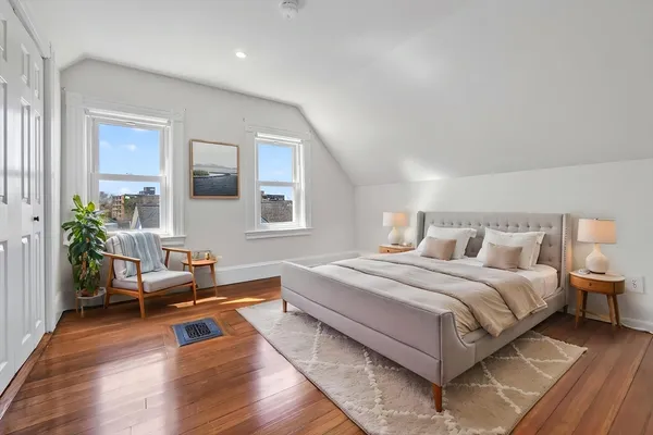 a bedroom with a bed wooden floor and windows
