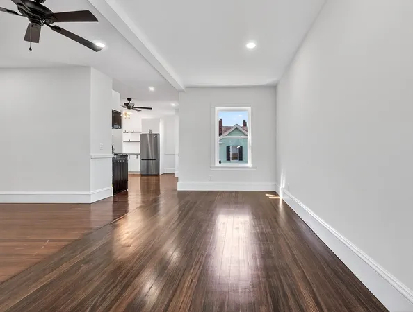 a view of empty room with a window and wooden floor