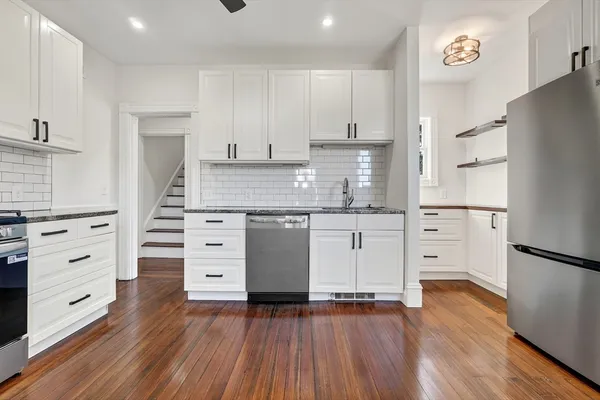 a kitchen with stainless steel appliances white cabinets and wooden floors