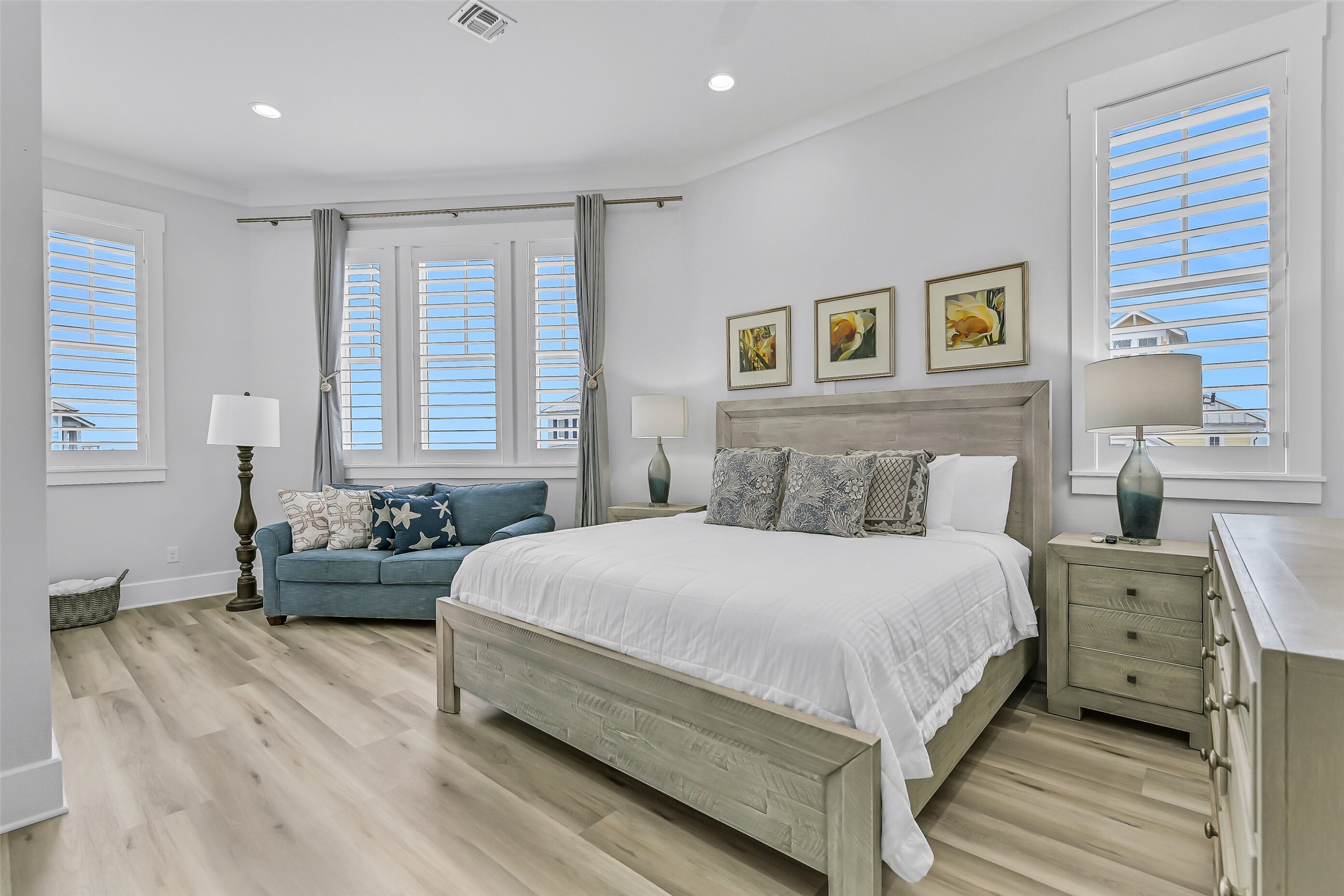 817 Positano Road Galveston, TX 77550 - Photo 4 of 50 This spacious primary suite offers a relaxing coastal retreat after a day at the beach. Recently refreshed with updated furnishings, a new media console, and additional accent pieces, the room combines comfort, style, and functionality. Large windows, a sitting area, and new beach-inspired flooring create a bright, inviting atmosphere that perfectly complements the home's elevated coastal design.