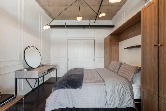 a bedroom with a bed a mirror with the wooden floor