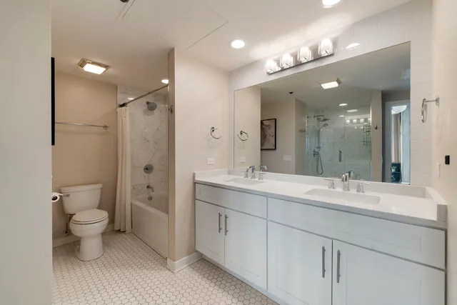 a spacious bathroom with a toilet sink double and mirror
