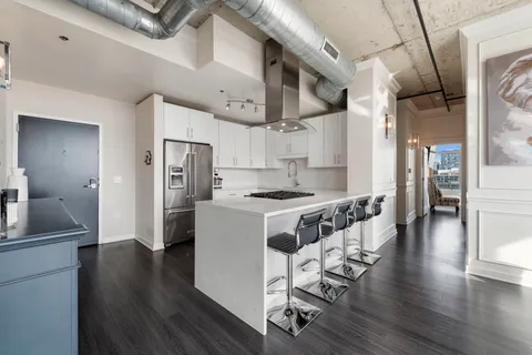 a kitchen with stainless steel appliances granite countertop a refrigerator a sink dishwasher a stove and white cabinets with wooden floor