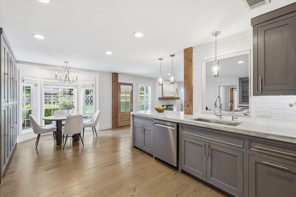 4310 Forest Bend Road Dallas, TX 75244 - Photo 13 of 40 Kitchen featuring a spacious island with a built-in sink, gray cabinetry, stainless steel appliances, and a white subway tile backsplash