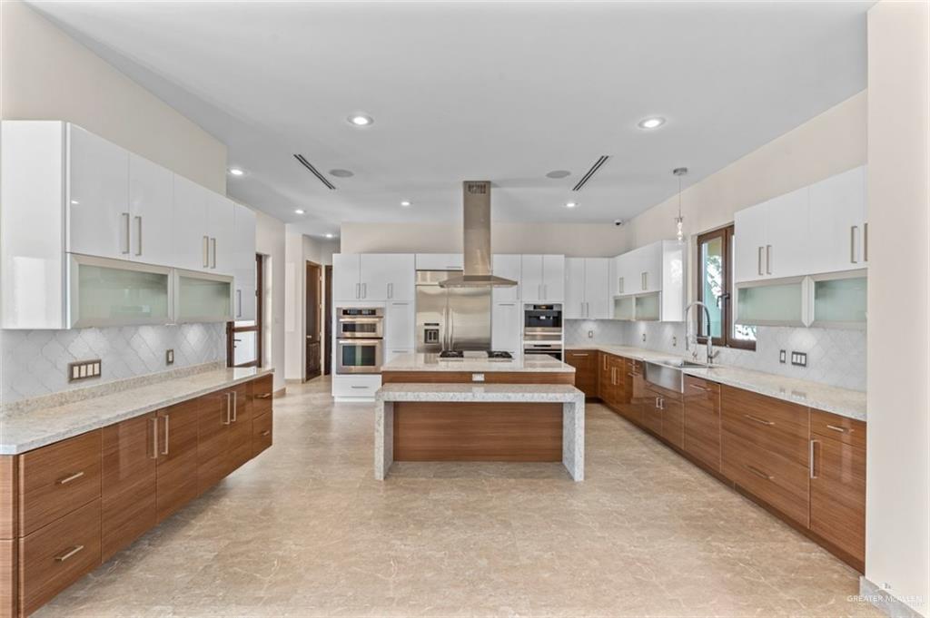 1421 Encanto Road, Unit SERVICE Weslaco, TX 78596 - Photo 32 of 37 a large kitchen with kitchen island a large counter space a sink stainless steel appliances and cabinets