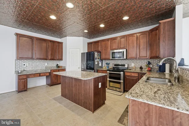 a kitchen with stainless steel appliances granite countertop wooden cabinets sink stove and microwave