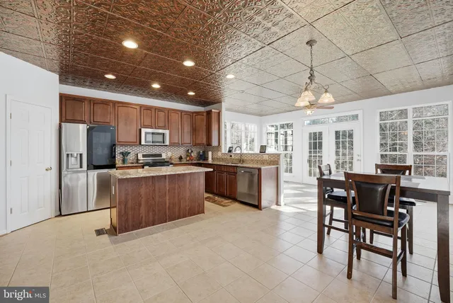 a kitchen with stainless steel appliances a refrigerator a stove a sink a dining table and chairs