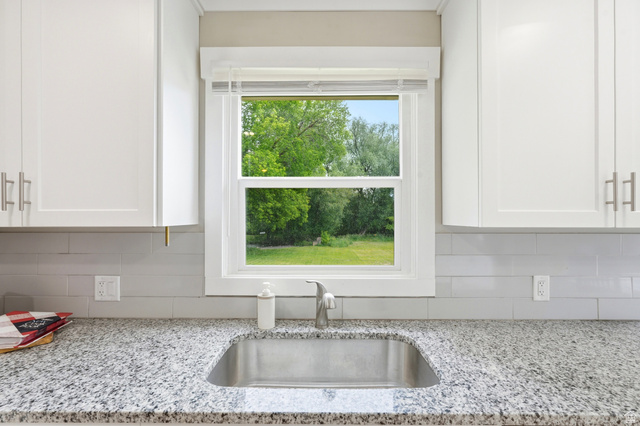 778 East 200 North Logan, UT 84321 - Photo 20 of 43 Kitchen sink area featuring an undermount stainless steel sink, speckled granite countertop, white shaker cabinetry with brushed nickel hardware, and a light gray subway tile backsplash