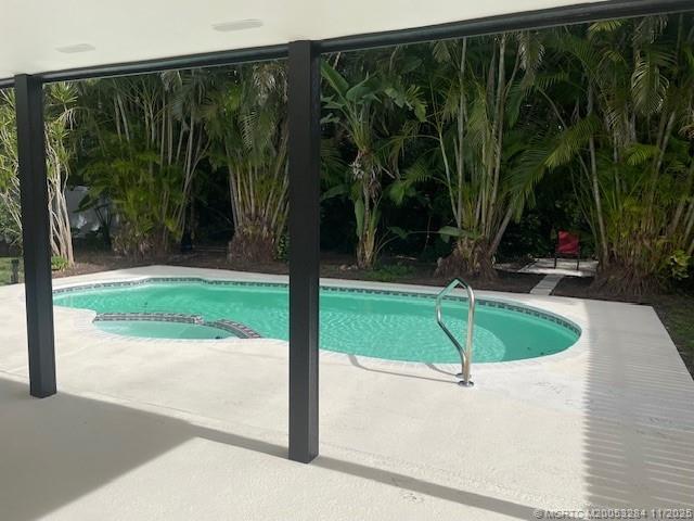 5549 Southeast Normandy Avenue Stuart, FL 34997 - Photo 18 of 21 a view of a swimming pool with a garden and patio