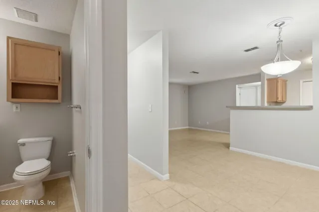 an empty room with chandelier fan and windows