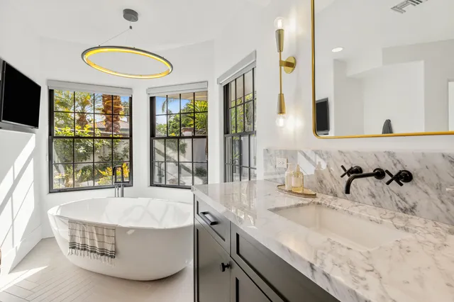 a living room with furniture a large window and potted plants