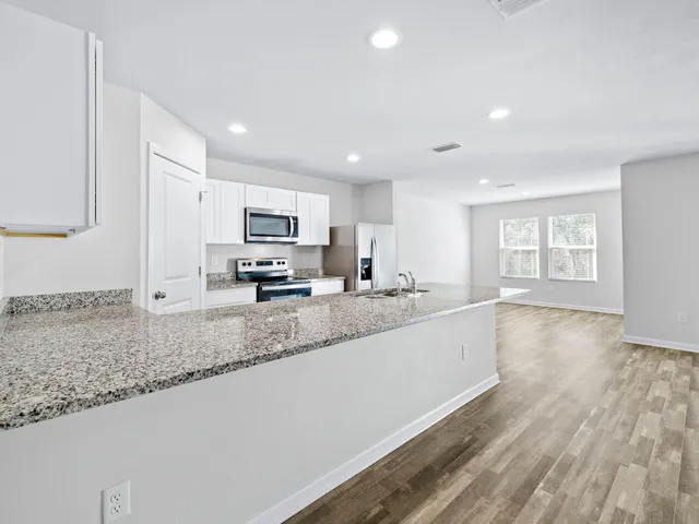 a kitchen with stainless steel appliances granite countertop a stove a refrigerator and a microwave oven