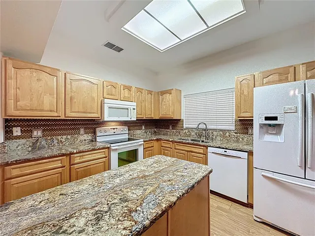 a view of an empty room with chandelier fan and fire place