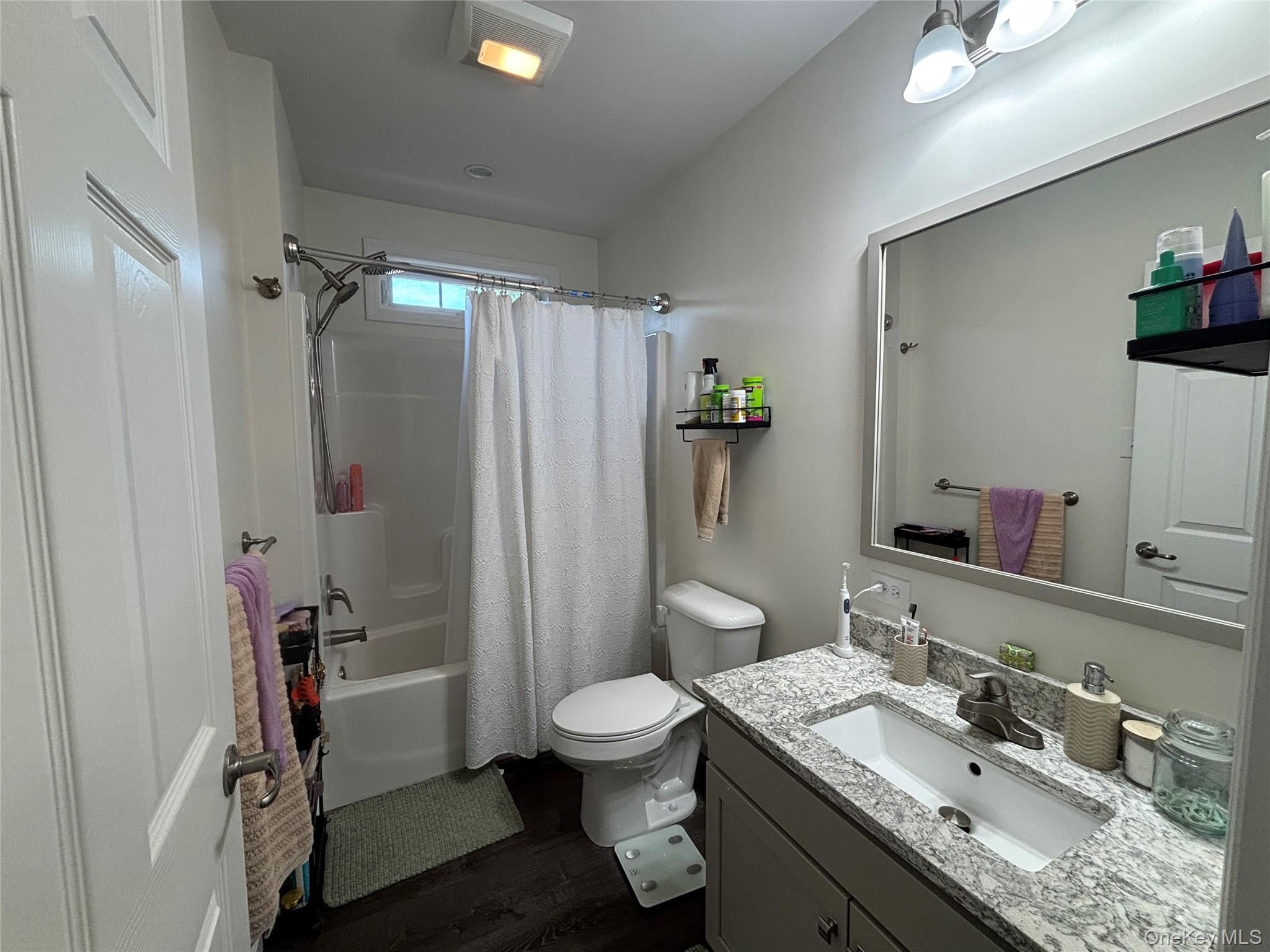 1661 Old Country Road, Unit 563 Riverhead, NY 11901 - Photo 18 of 43 a bathroom with a granite countertop sink toilet a shower and a mirror