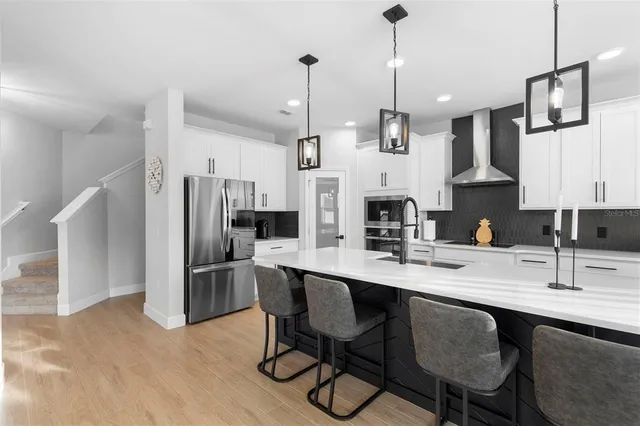 a kitchen with stainless steel appliances kitchen island granite countertop a table chairs and a refrigerator