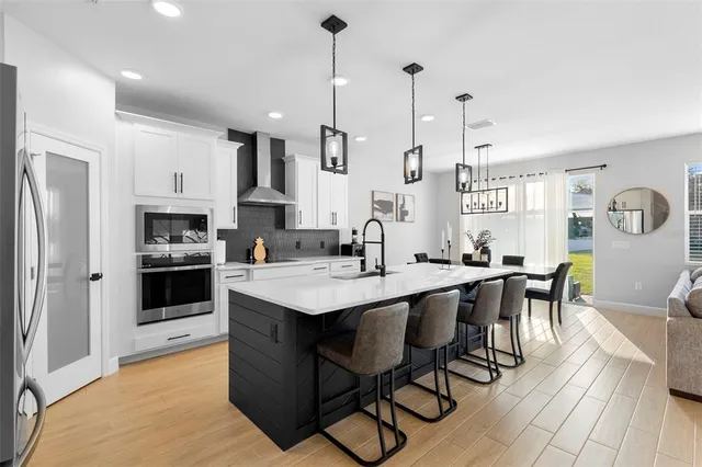 a kitchen with stainless steel appliances kitchen island a table chairs sink and cabinets