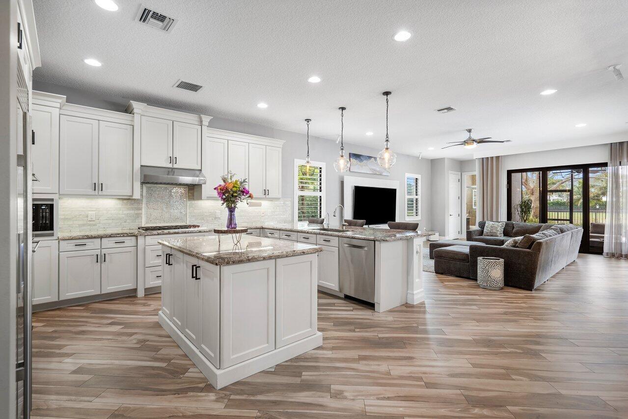 16857 Pierre Circle Delray Beach, FL 33446 - Photo 11 of 57 a kitchen with kitchen island granite countertop a stove top oven a sink dishwasher a dining table and chairs with wooden floor