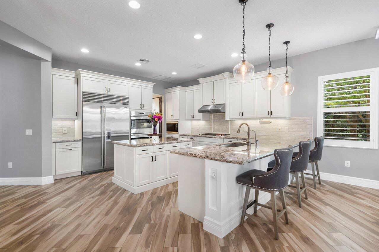 16857 Pierre Circle Delray Beach, FL 33446 - Photo 12 of 57 a kitchen with kitchen island granite countertop wooden floors and white cabinets