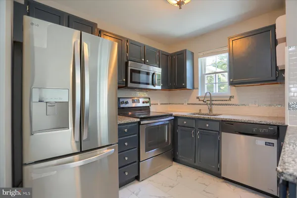 a kitchen with stainless steel appliances granite countertop a refrigerator stove and sink