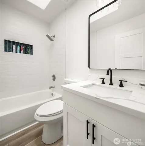 a bathroom with a bathtub shower sink vanity mirror and toilet
