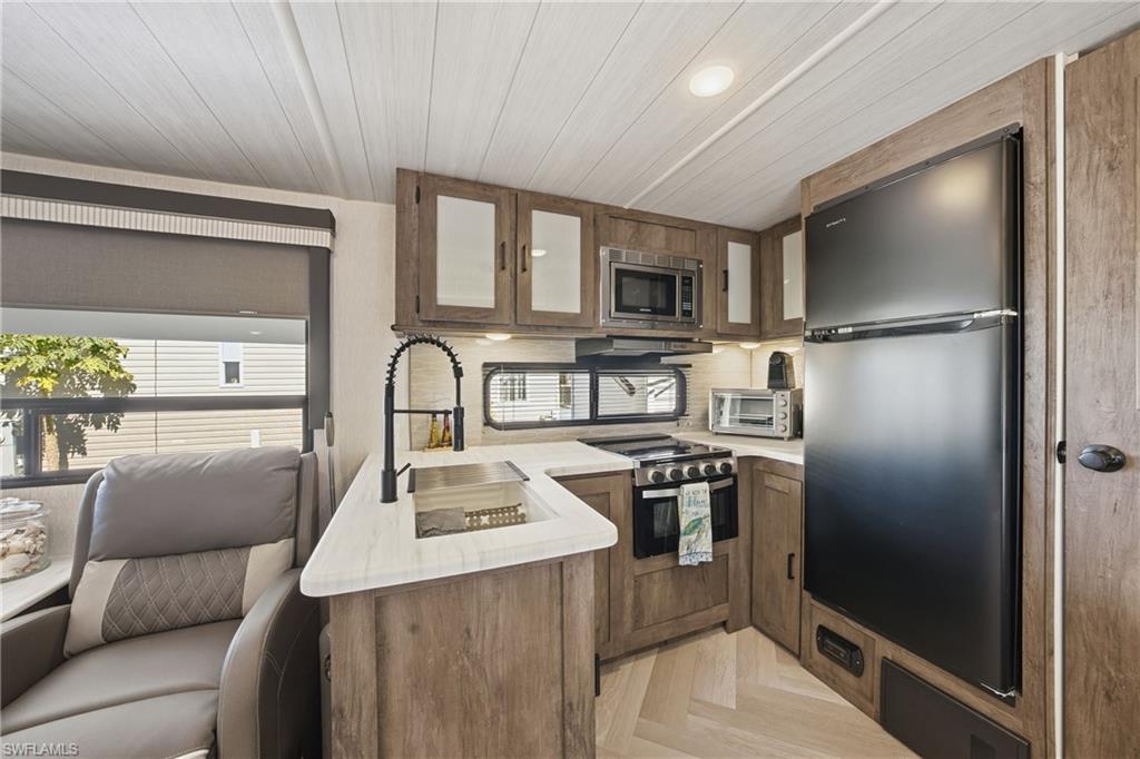 26 Bass Lane Naples, FL 34114 - Photo 26 of 26 Kitchen with stainless steel appliances, open floor plan, parquet flooring, a peninsula, and glass insert cabinets