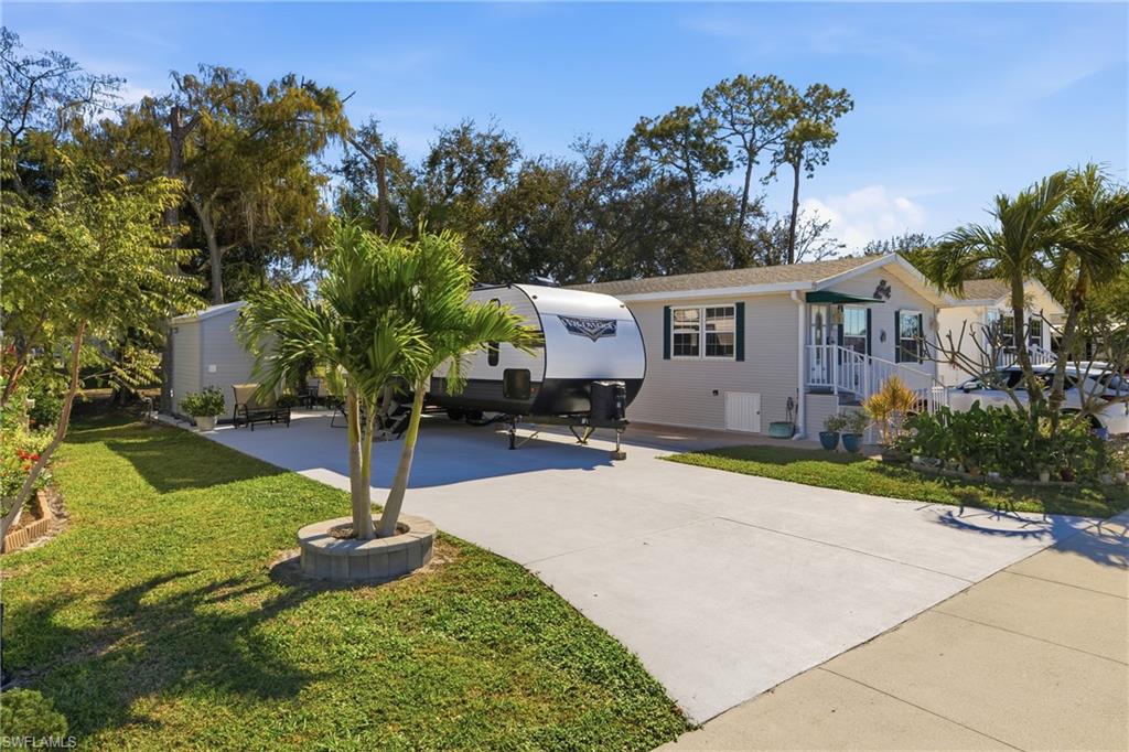 26 Bass Lane Naples, FL 34114 - Photo 2 of 26 View of front of property with concrete driveway, a patio area, and a front yard