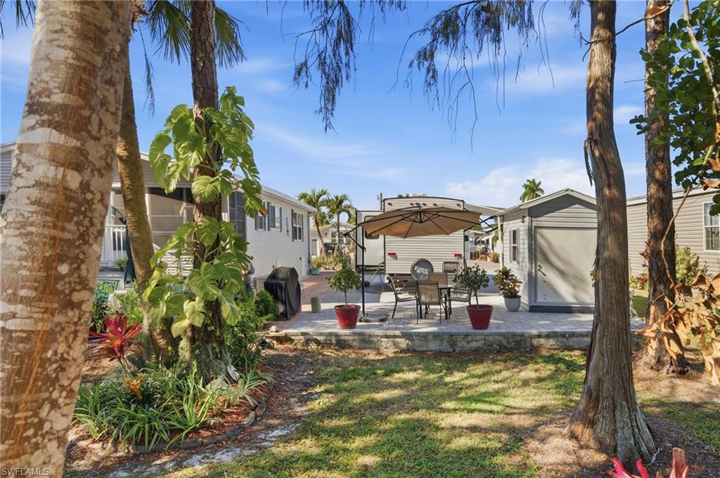 26 Bass Lane Naples, FL 34114 - Photo 3 of 26 View of green lawn featuring a patio area, a storage shed, and outdoor dining area