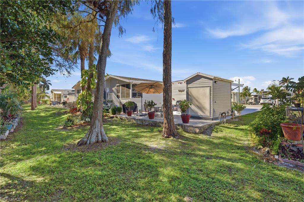 26 Bass Lane Naples, FL 34114 - Photo 5 of 26 Rear view of house featuring a patio, a yard, and a shed
