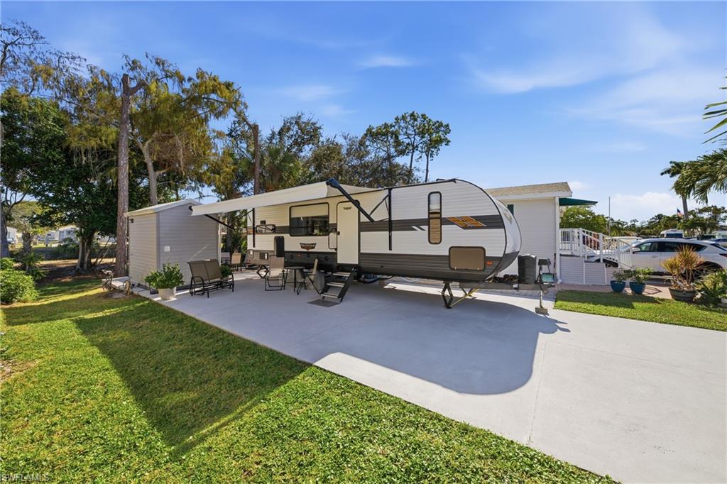 26 Bass Lane Naples, FL 34114 - Photo 9 of 26 Back of house featuring a lawn and a patio area