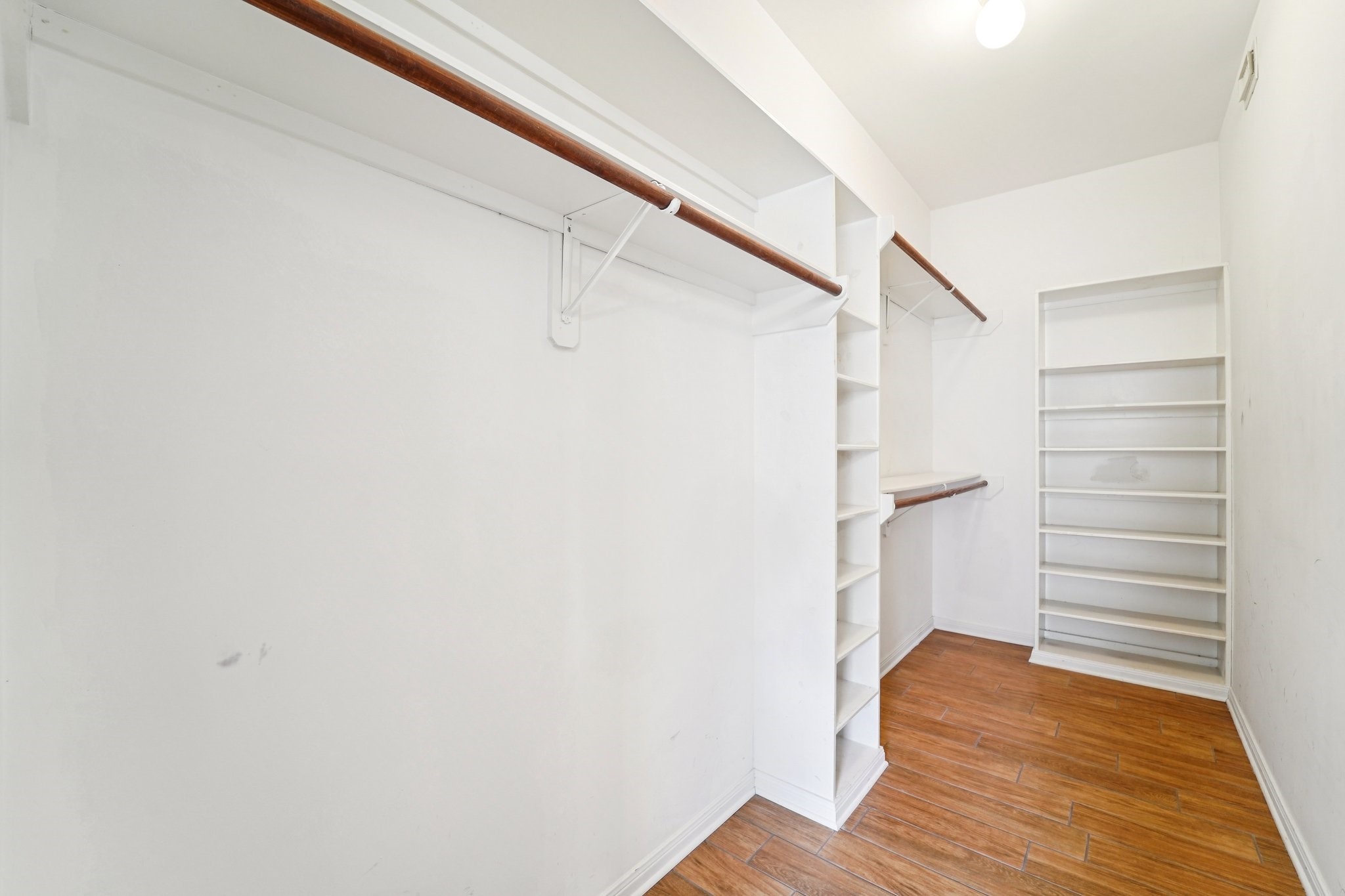 14420 Walters Road, Unit 55 Houston, TX 77014 - Photo 23 of 35 Spacious walk-in closet with wood flooring, ample shelving, and multiple hanging rods for organized storage.