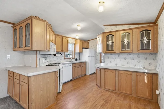 a kitchen with kitchen island granite countertop wooden cabinets and white appliances