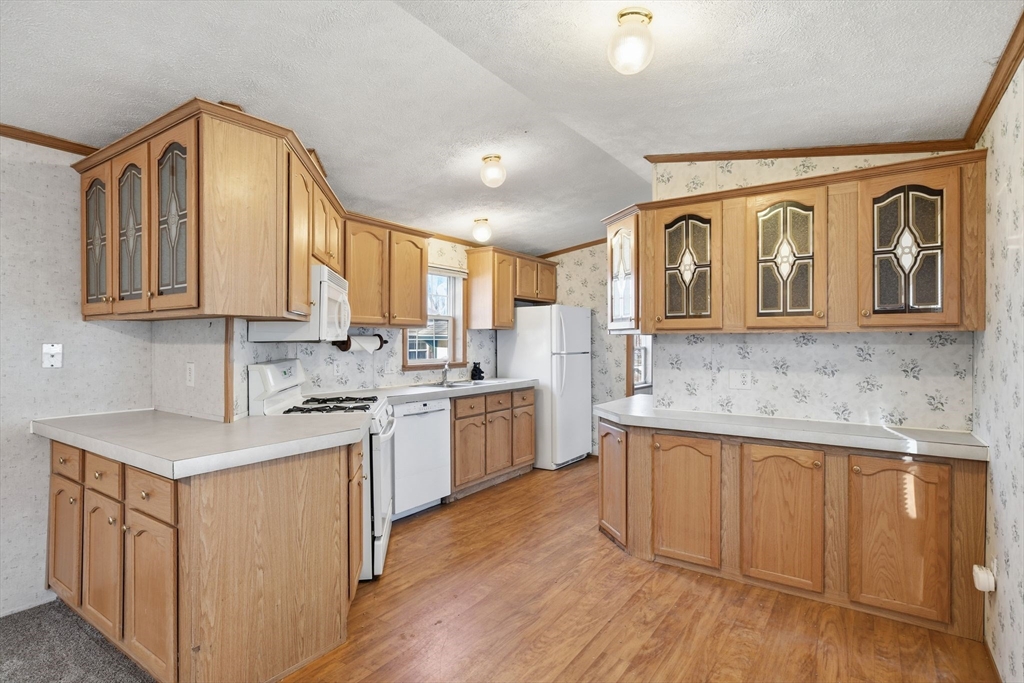 15 Quaboag Valley, Unit 15 Sudbury, MA 01776 - Photo 9 of 35 a kitchen with kitchen island granite countertop wooden cabinets and white appliances