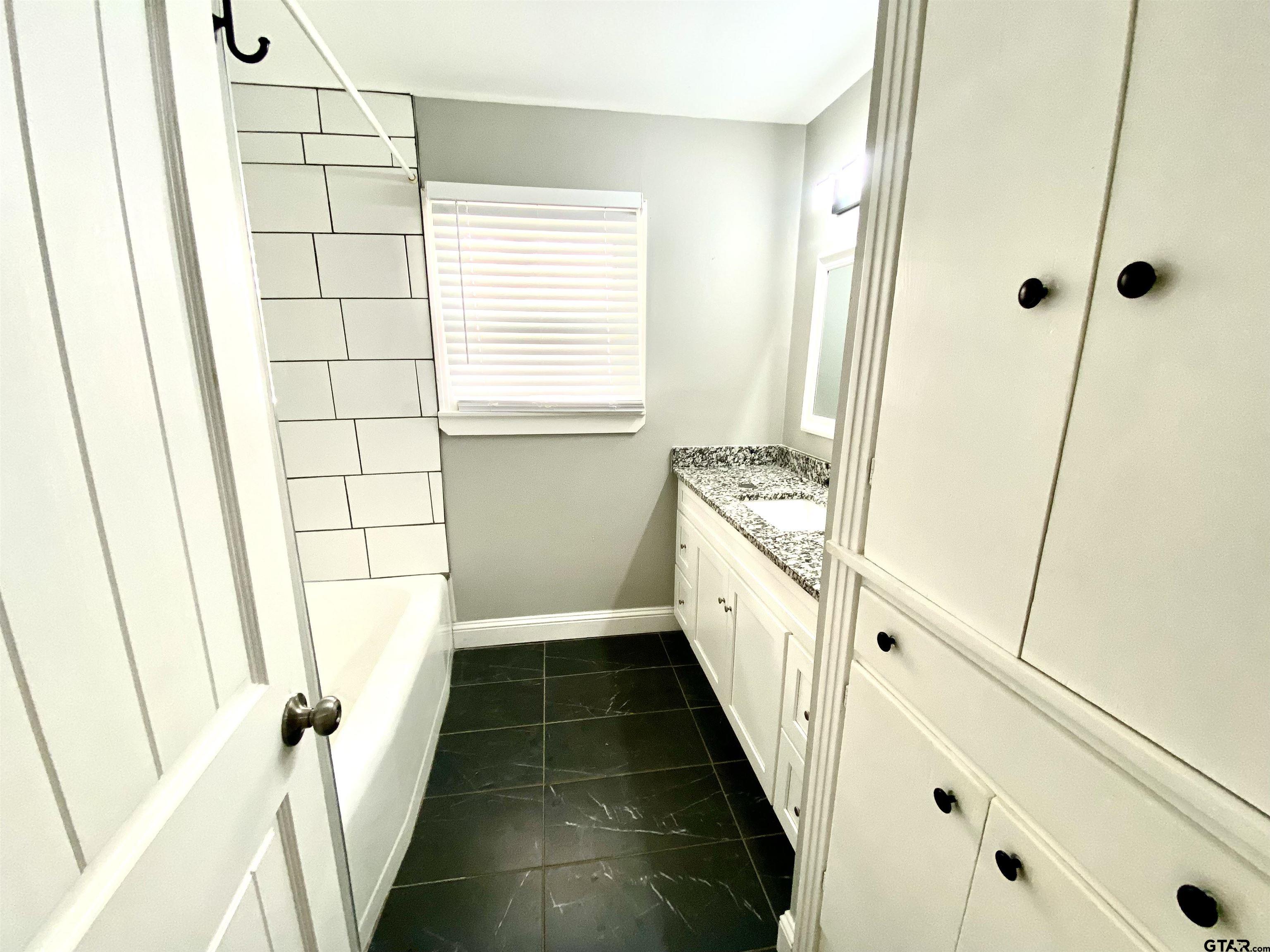 1914 Parklen Street Tyler, TX 75701 - Photo 30 of 39 a bathroom with a sink a toilet a window and vanity