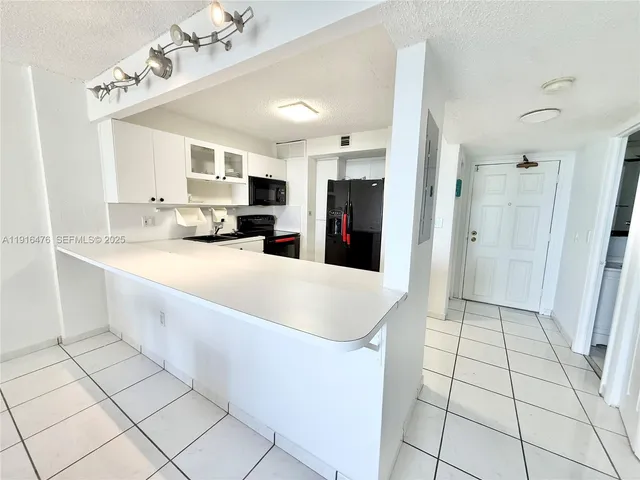 a kitchen with a sink dishwasher and white cabinets with wooden floor