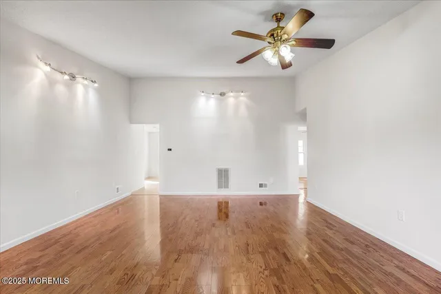 a view of an empty room with window and wooden floor