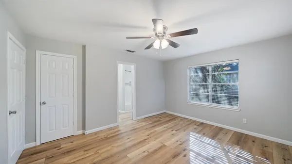 a view of empty room with wooden floor and fan