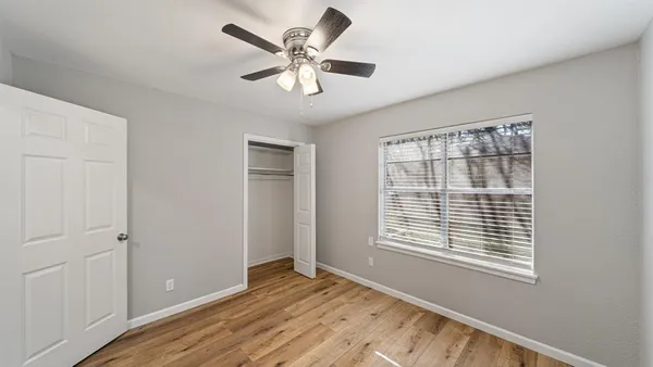 a view of an empty room with a window and a kitchen