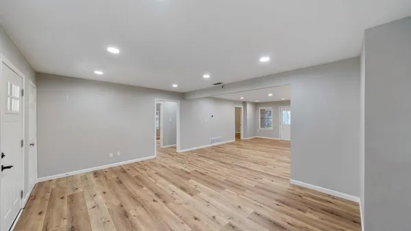 a view of an empty room with wooden floor and closet