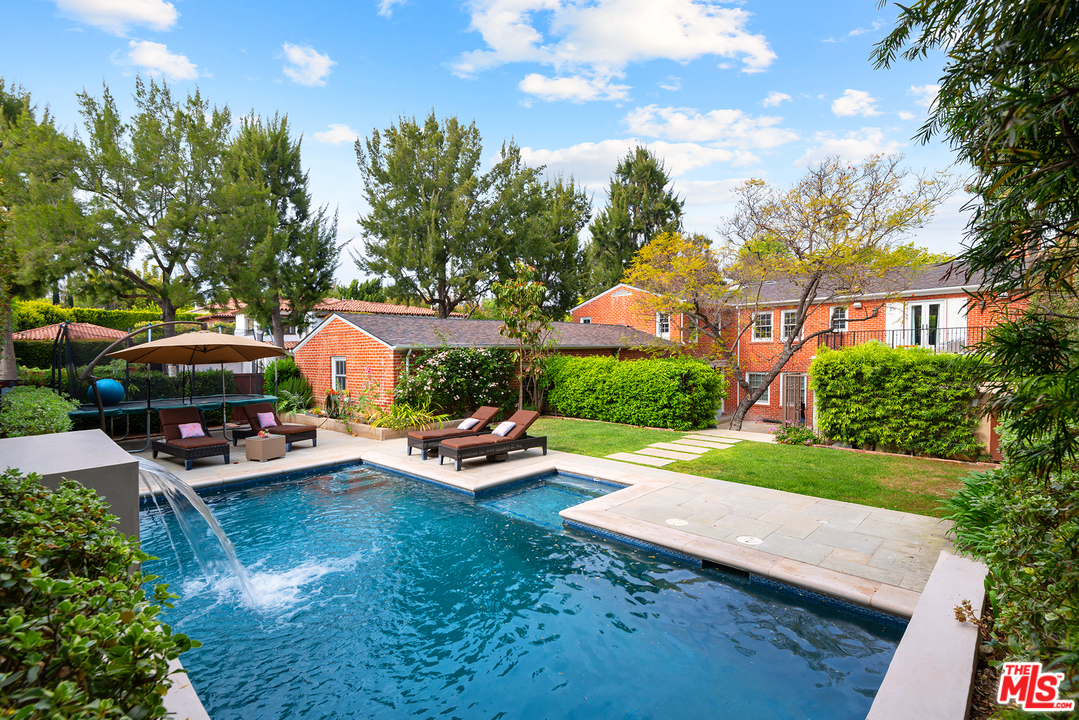a view of a yard with lawn chairs and large trees