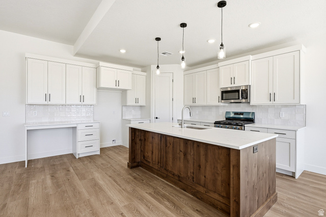 4978 North 75 East Enoch, UT 84721 - Photo 9 of 60 Kitchen with stainless steel appliances, a kitchen island with sink, decorative light fixtures, two tone color scheme, and light stone countertops